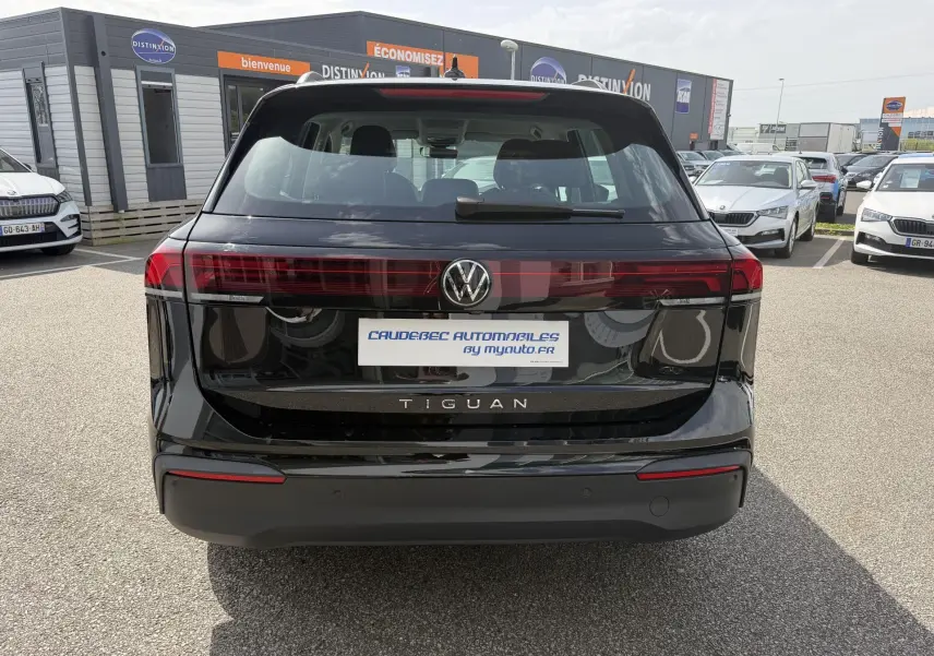 Vue arrière d'un Volkswagen Tiguan noir 2025 avec feux arrière LED et logo VW centré sur un parking extérieur.