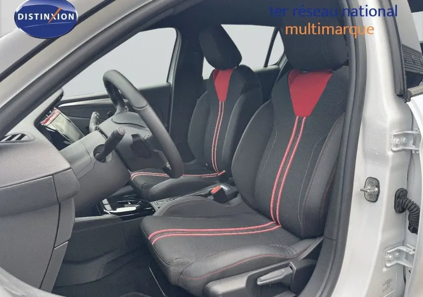 Vue intérieure côté conducteur d'une Opel Corsa blanche 2022 avec sièges noirs et rouges à surpiqûres rouges.