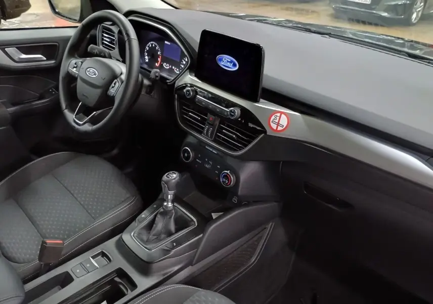 Intérieur avant droit du Ford Kuga 2024 noir Obsidien, volant cuir multifonctions et écran tactile central allumé Ford.