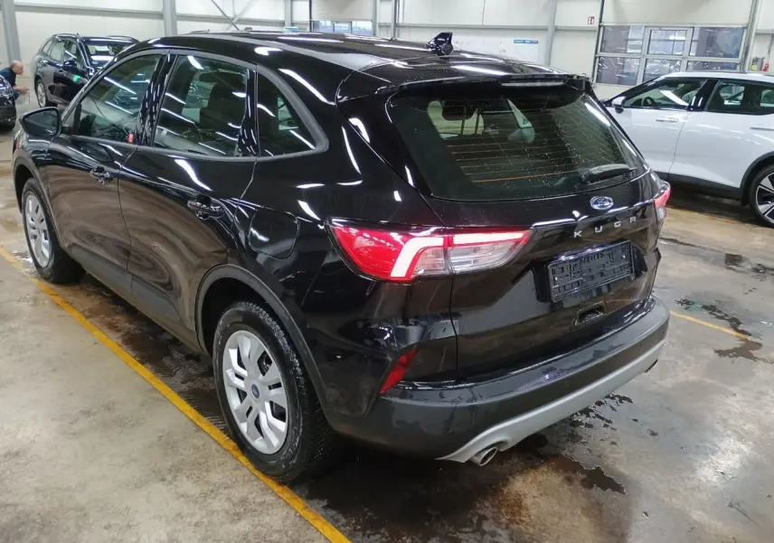 Vue 3/4 arrière droite du Ford Kuga noir Obsidien 2024, avec feux arrière allumés et jantes argentées.