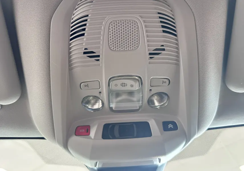 Vue en gros plan du plafonnier gris clair du Citroën C5 Aircross 2024 avec commandes d'éclairage et bouton SOS rouge.
