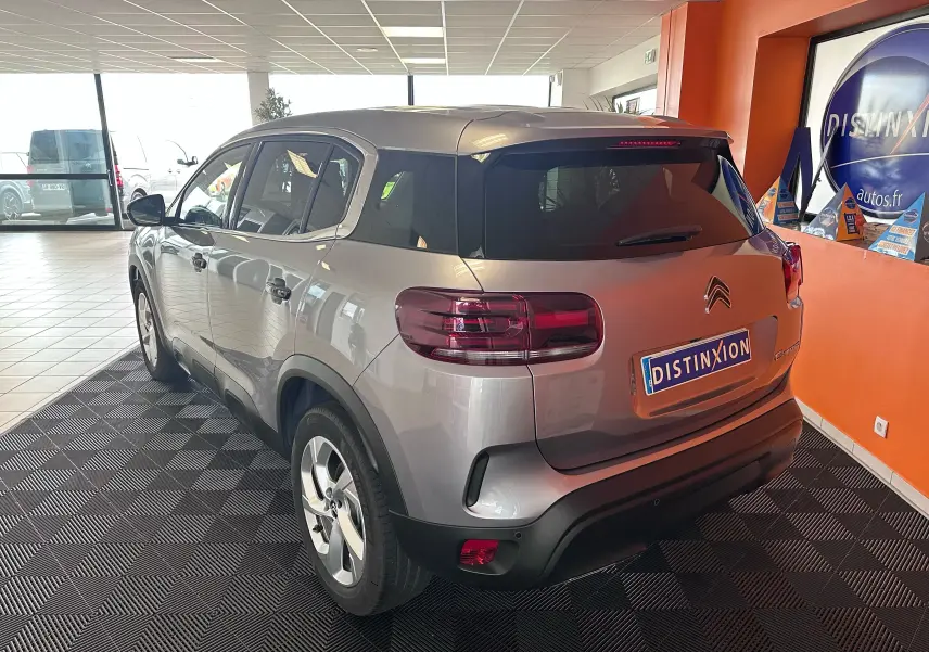Vue 3/4 arrière droite d’un Citroën C5 Aircross 2024 gris Artense avec vitres arrière surteintées en showroom.