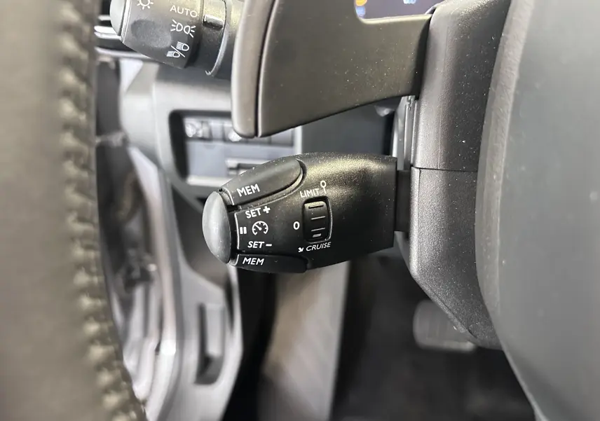 Gros plan sur la commande de régulateur de vitesse au volant cuir du Citroën C5 Aircross 2024 gris Artense.