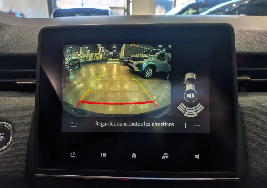 Écran central affichant la caméra de recul avec vue arrière sur un véhicule bleu Iron dans un garage lumineux.