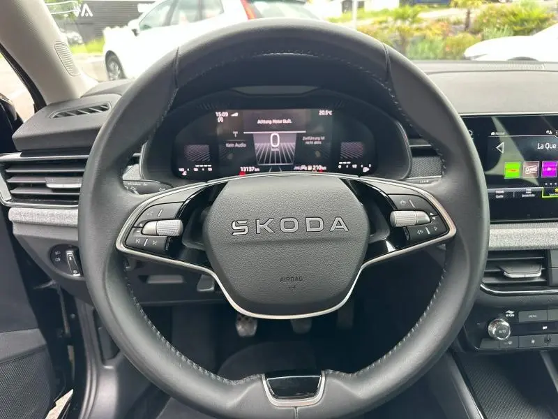 Vue centrée sur le volant cuir multifonction SKODA d'une Scala 2025 avec tableau de bord numérique et écran tactile.