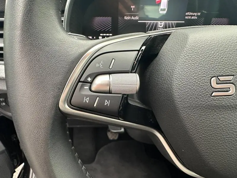 Gros plan sur la commande multimédia gauche du volant cuir noir du Skoda Scala 2025, avec molette métallique texturée.