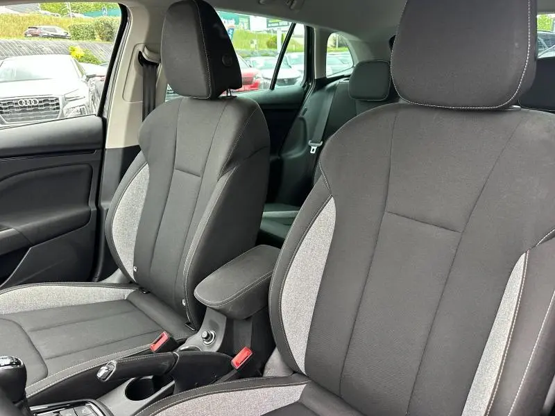 Vue intérieure sur les sièges avant tissu noir et gris avec accoudoir central de la Skoda Scala 2025 Noir Magic nacré.