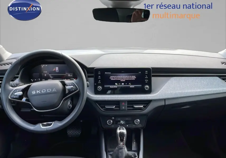 Vue intérieure frontale du tableau de bord gris noir et volant multifonction d’une Skoda Scala blanc glacier 2025.