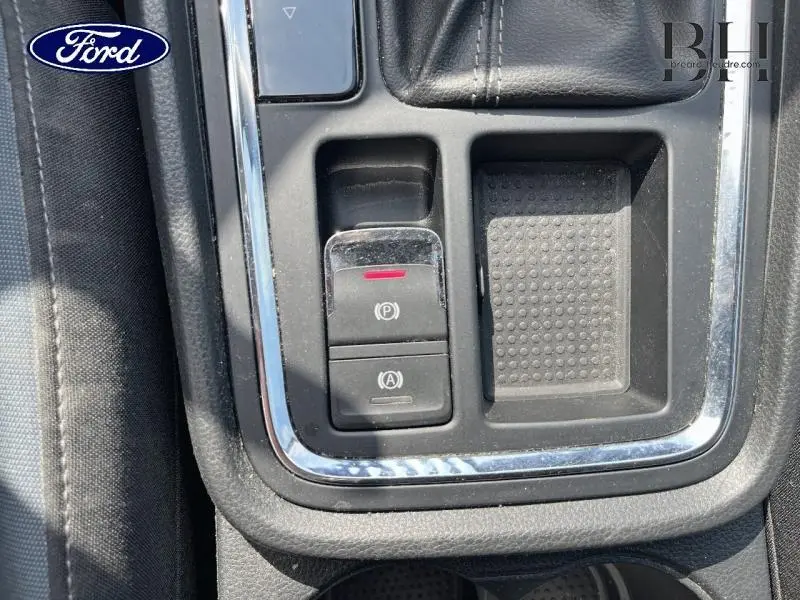 Gros plan sur la console centrale noire du SEAT Ateca blanc Nevada, mettant en valeur les commandes de frein à main électronique et d'arrêt auto.