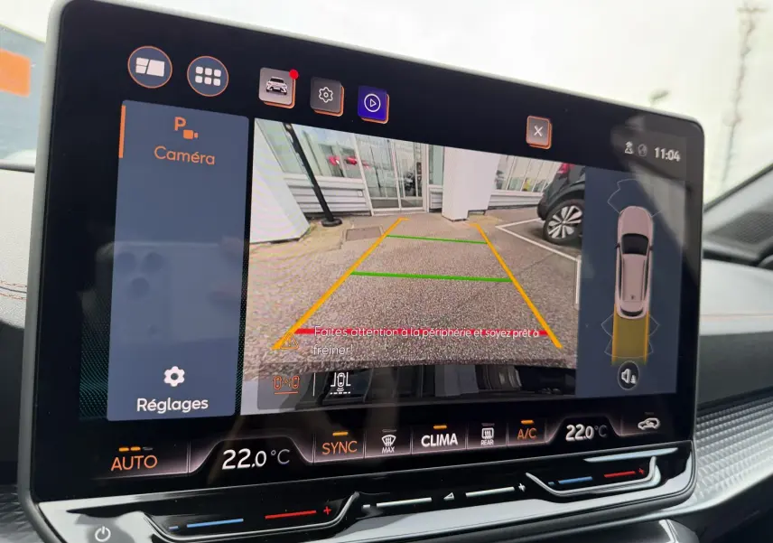 Écran tactile intérieur montrant la caméra de recul et l’aide au stationnement du CUPRA Formentor bleu, vue de face.