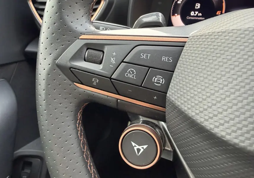Gros plan sur le volant cuir perforé du CUPRA Formentor avec commandes multifonctions et logo CUPRA central.