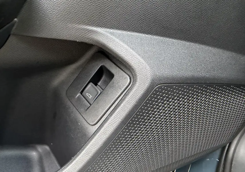 Détail intérieur du bouton d'ouverture du hayon dans un panneau noir texturé du CUPRA Formentor bleu 2025.