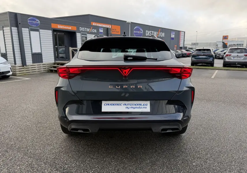 Vue arrière d'une CUPRA Formentor bleu foncé avec bandeau lumineux arrière et double sortie d'échappement noire.