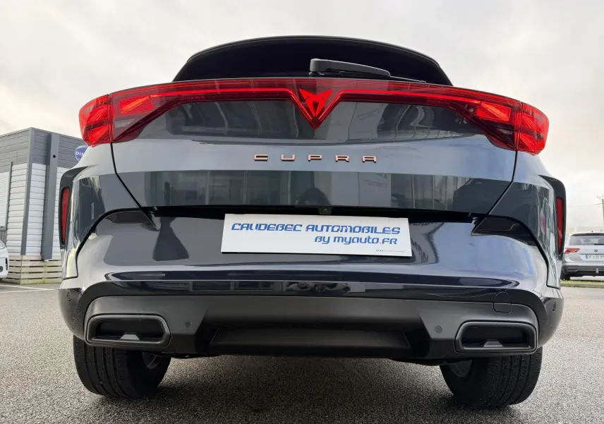 Vue arrière centrée du CUPRA Formentor bleu métallisé avec bandeau lumineux rouge et double sortie d'échappement noire stylisée.
