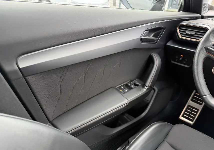 Vue intérieure côté conducteur de la porte noire du CUPRA Formentor avec commandes de vitres et poignée en cuir.