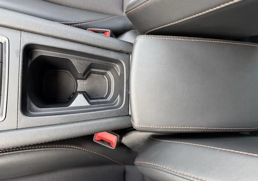 Gros plan sur la console centrale noire avec porte-gobelets et accoudoirs en cuir noir surpiqué orange du CUPRA Formentor.