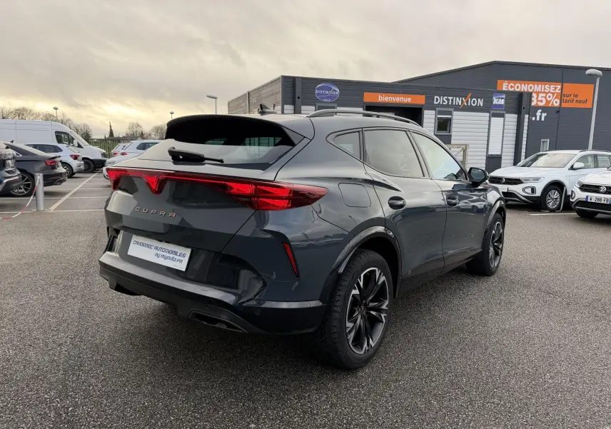 Vue 3/4 arrière droite d'un CUPRA Formentor bleu métallisé avec feux arrière en bandeau lumineux et jantes noires stylisées.