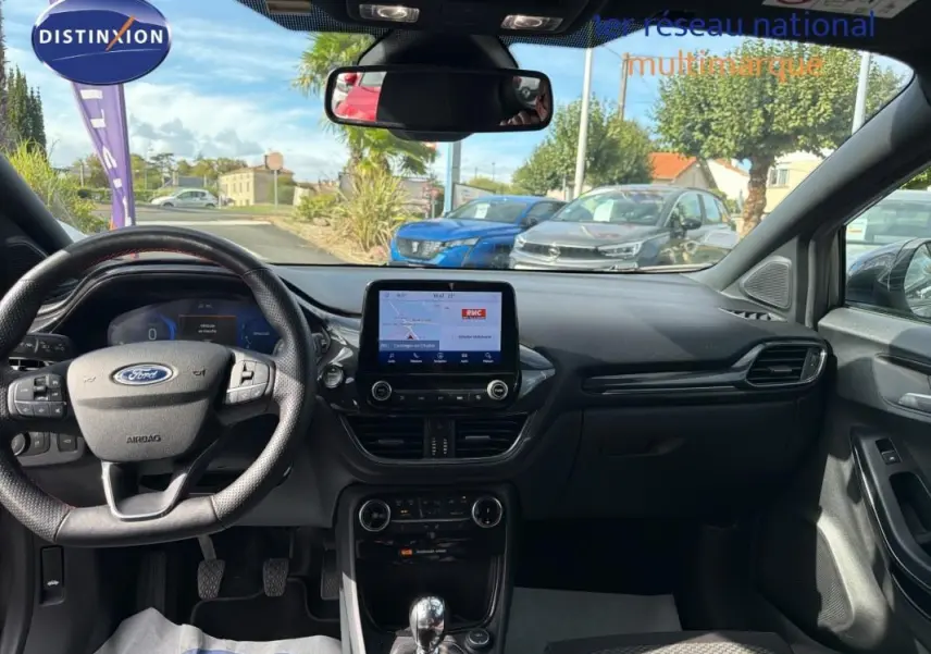 Vue intérieure avant du Ford Puma 2022 gris foncé, avec tableau de bord moderne et écran tactile central allumé.