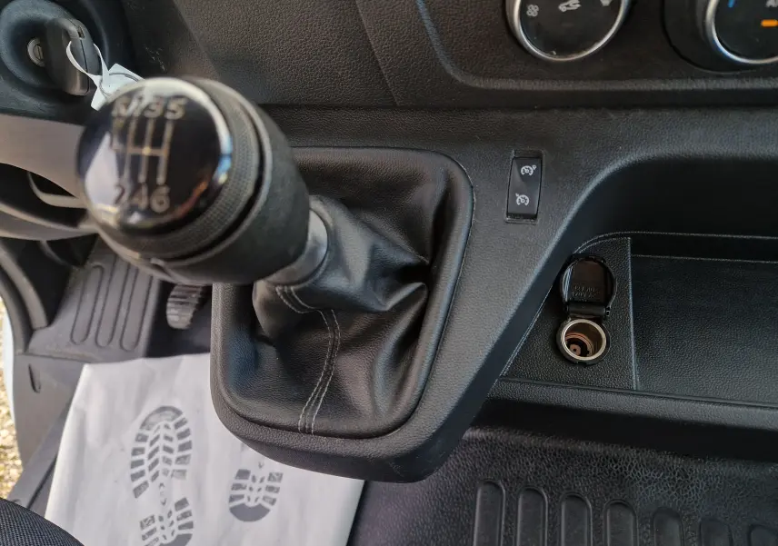 Gros plan sur le levier de vitesses manuel et la prise 12V du tableau de bord du Renault Master blanc 2023.