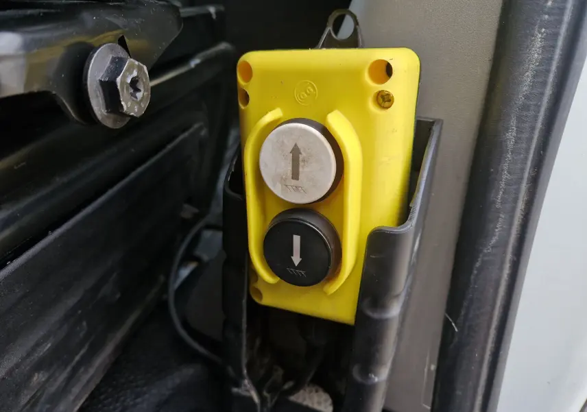 Gros plan sur les boutons jaune et noir de commande de benne du Renault Master Châssis Double Cabine blanc 2023.