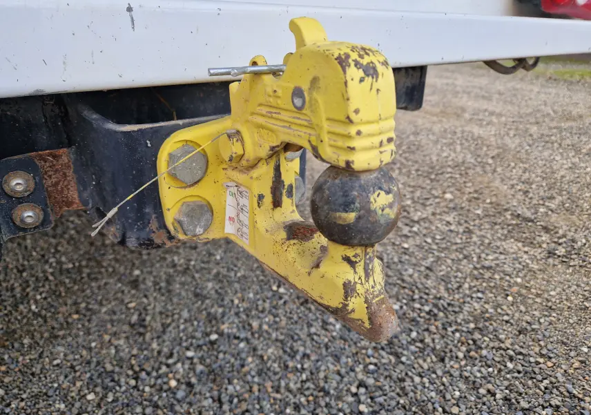 Gros plan sur l'attelage jaune usé fixé à l'arrière blanc d'un Renault Master Chassis Dble Cab 2023.