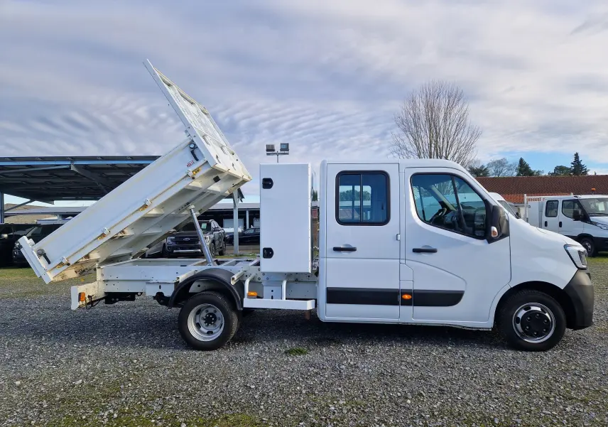 Vue de profil côté gauche d’un Renault Master blanc 2023 avec benne relevée et coffre latéral sur châssis double cabine.