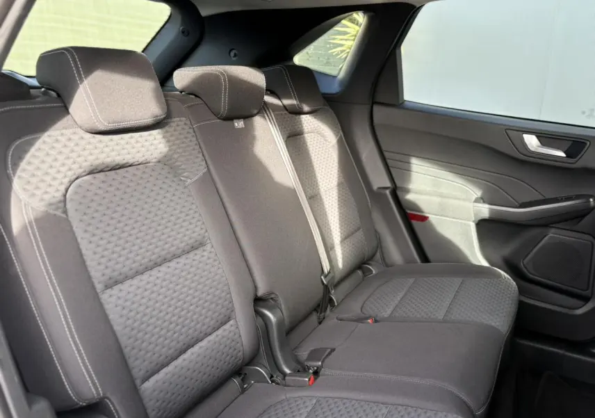 Vue intérieure côté droit des sièges arrière en tissu gris du Ford Kuga 2024, avec ceinture de sécurité et porte.