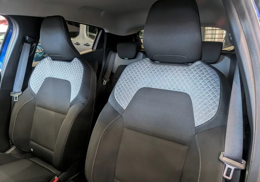 Gros plan sur les sièges avant en tissu noir et gris avec surpiqûres, intérieur de la Renault Clio V Bleu Iron 2025.