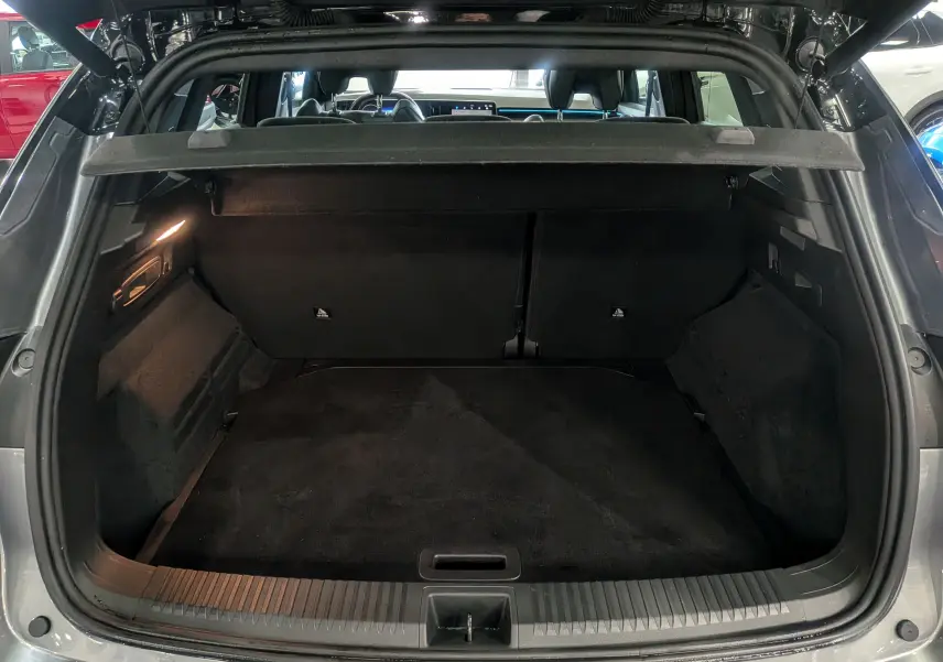 Coffre ouvert vu de l'arrière d'un Renault Austral gris schiste avec toit noir, intérieur spacieux et tapis noir.