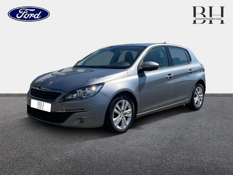 Peugeot 308 gris Artense vue 3/4 avant droit sur fond neutre, jantes alliage et feux avant visibles.
