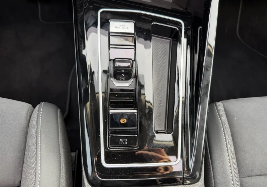Vue rapprochée de la console centrale noire brillante avec sélecteur de vitesses et commandes électroniques d'une Volkswagen Golf SW.