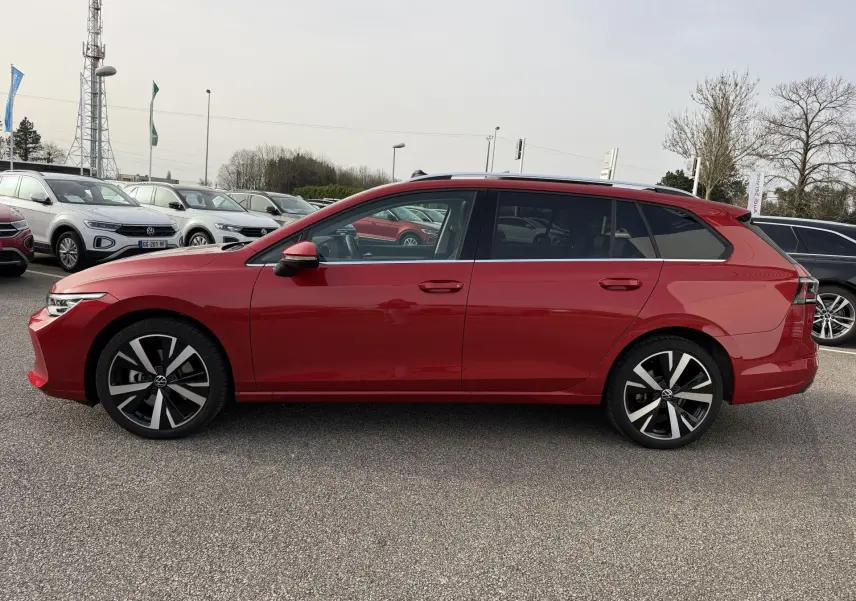 Profil droit d'une Volkswagen Golf SW rouge métallisée 2025 avec jantes alliage noir brillant et toit panoramique.