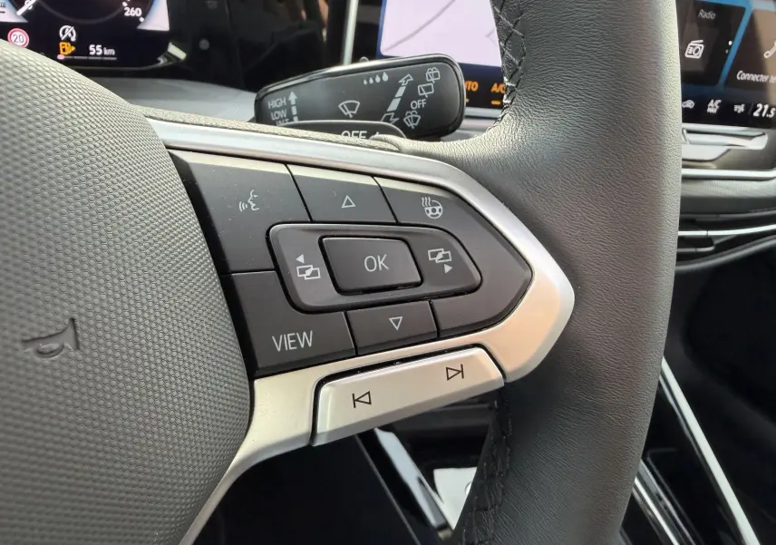 Gros plan sur les commandes multifonctions du volant cuir d'une Volkswagen Golf SW 2.0 TDI 2025, intérieur noir.