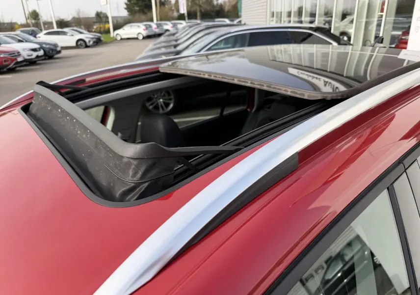 Toit ouvrant panoramique ouvert sur une Volkswagen Golf SW rouge, vue en léger plongé côté avant droit.
