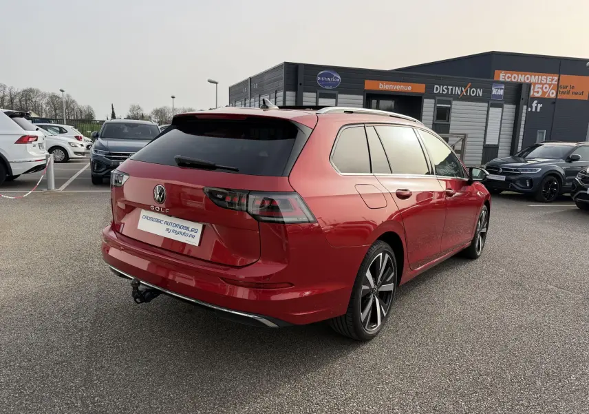 Volkswagen Golf SW rouge vue 3/4 arrière droit avec jantes alliage noir brillant et attelage rabattable.
