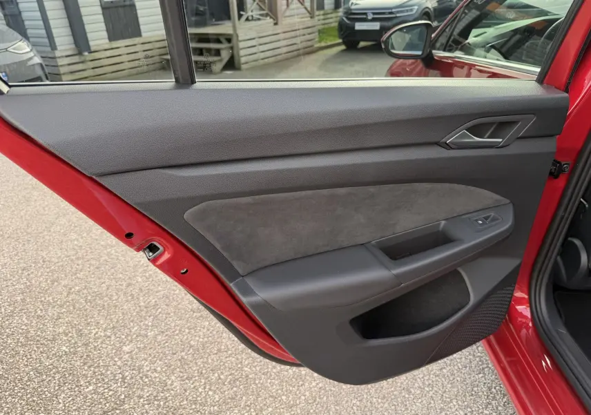 Vue latérale de la porte arrière gauche rouge ouverte d'une Volkswagen Golf SW avec garniture intérieure noire et grise.
