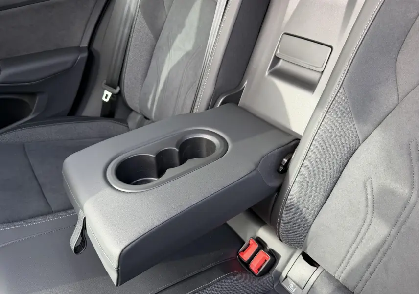 Accoudoir central arrière déployé avec porte-gobelets, sièges tissu gris foncé de la Volkswagen Golf SW 2025.