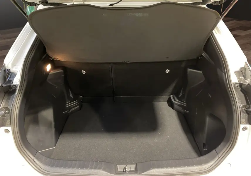 Coffre ouvert vu de l'arrière d'une Toyota Yaris Cross blanche, espace de chargement propre et éclairé.