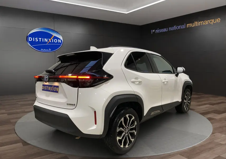 Toyota Yaris Cross blanc vue 3/4 arrière droit, jantes alu 17 pouces et feux arrière LED allumés.