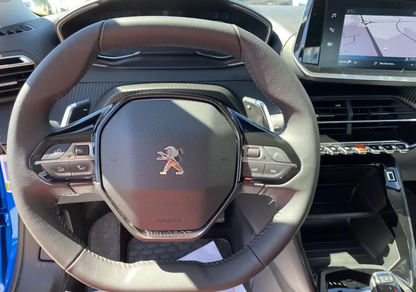 Vue rapprochée du volant cuir noir et du tableau de bord avec écran tactile du Peugeot 2008 bleu Vertigo 2021.
