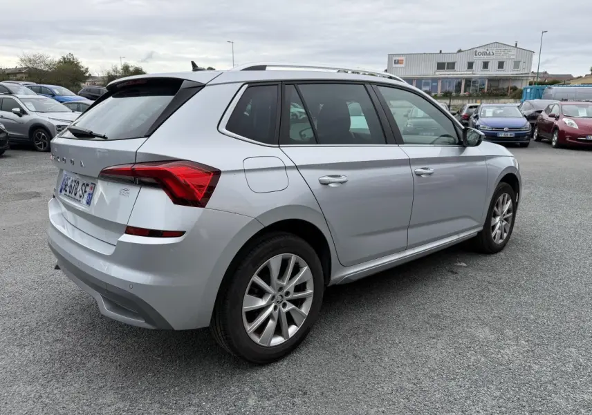Vue 3/4 arrière droite d'un Skoda Kamiq gris métallisé avec jantes alliage 17'' sur un parking extérieur.