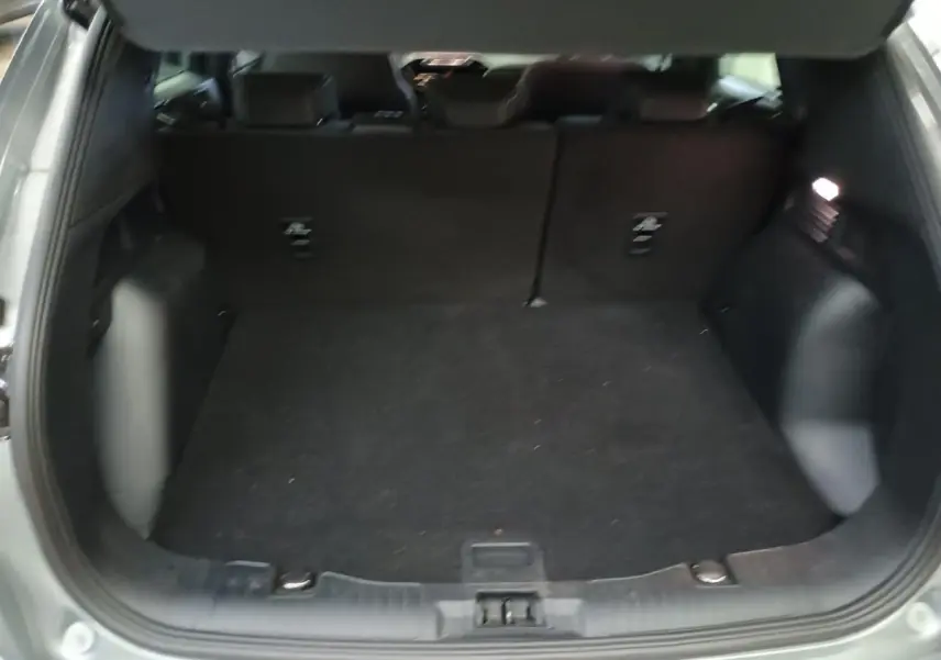 Coffre ouvert d'un Ford Kuga gris Solar 2024, vue intérieure arrière montrant un espace de chargement spacieux.