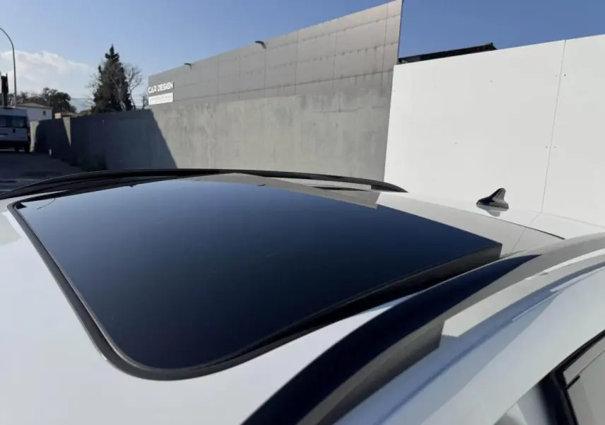 Vue rapprochée du toit ouvrant panoramique noir sur un CUPRA Formentor blanc nacré avec rails de toit noirs.