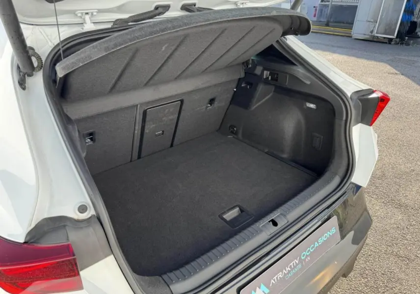 Coffre ouvert vu de l'arrière d'une CUPRA Formentor blanc nacré avec intérieur noir et feux arrière rouges.
