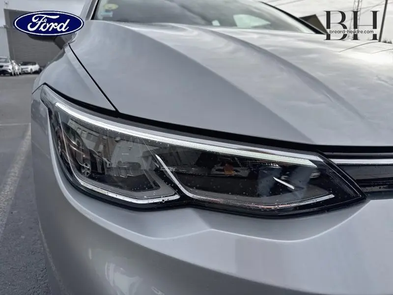 Gros plan sur le phare avant gauche gris lunaire de la Volkswagen Golf 2023 avec signature lumineuse LED distinctive.