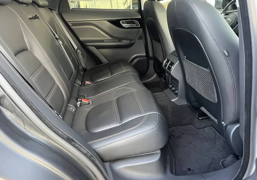 Vue côté gauche de l'habitacle arrière du Jaguar F-PACE 240D Prestige 2018 avec sièges cuir noir et surpiqûres contrastées.