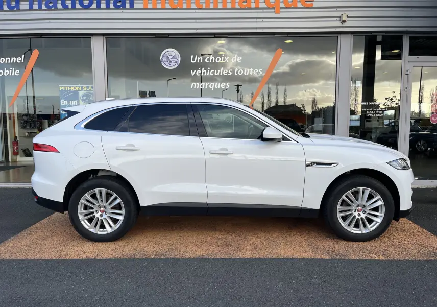Vue de profil côté gauche d'un Jaguar F-PACE blanc de 2018, SUV élégant avec jantes alliage et vitres teintées.