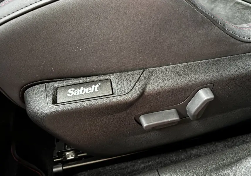 Détail du réglage de siège noir avec logo Sabelt sur Alfa Romeo Junior 1.2 Ibrida 2024, intérieur sombre.