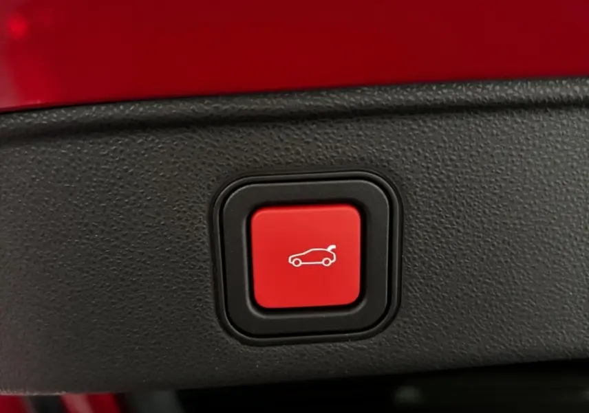 Gros plan sur le bouton rouge d'ouverture électrique du coffre d'une Alfa Romeo Junior rouge 2024.
