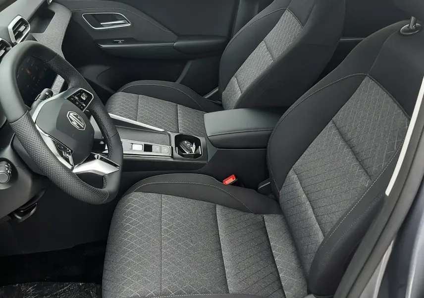 Vue intérieure côté conducteur du MG Motor ZS 1.5 Hybrid+ 197ch 2026, sièges tissu gris Camden Grey avec console centrale moderne.